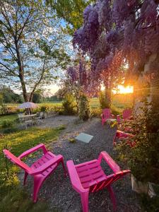a group of pink tables and chairs in a garden at La chambre magique in Masseret