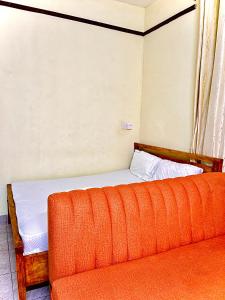a bed with an orange couch in a room at Studio Kilifi -Pendoraha Homes in Kilifi