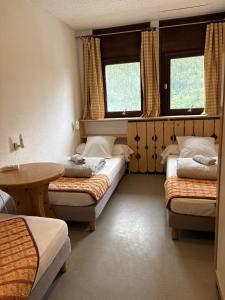 a room with three beds and a table and two windows at Alpenrose Chamonix in Chamonix