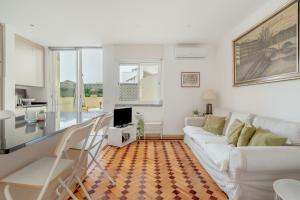a living room with a white couch and a television at Santarem Terrace by Homing in Santarém