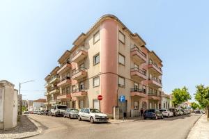 a pink building with cars parked on the side of a street at Santarem Terrace by Homing in Santarém