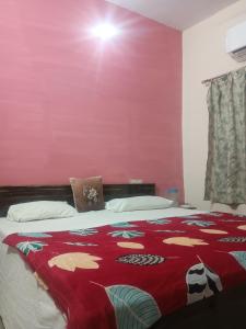 a bedroom with a bed with a red wall at Braj Pushp Guest House in Mathura