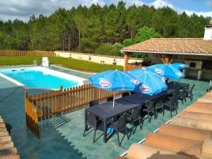 a table and chairs with umbrellas next to a pool at Seul au Monde in Guizengeard