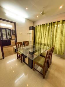 a dining room with a glass table and chairs at Grand Retreat in Trichūr +5 photos