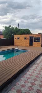 a swimming pool with a wooden deck next to a building at База отдыха Golden rest in Borovoye
