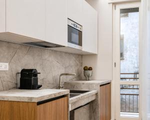 a kitchen with white cabinets and a sink at Numa Rome Condotti in Rome