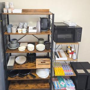 a kitchen shelf with dishes and a microwave at Snow Veil Iwamizawa in Iwamizawa