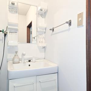 a white bathroom with a sink and a mirror at Snow Veil Iwamizawa in Iwamizawa