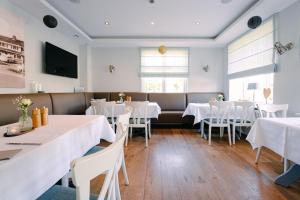 a dining room with white tables and white chairs at Hotel Waastwinj in Utersum