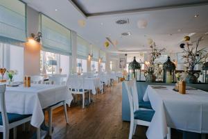 a dining room with white tables and chairs at Hotel Waastwinj in Utersum