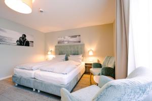 a hotel room with two beds and two chairs at Hotel Waastwinj in Utersum