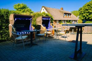 a patio with chairs and tables and a table and a house at Hotel Waastwinj in Utersum