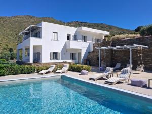 a villa with a swimming pool in front of a house at ELIA PRIVILEGED SUITES Andros ΑΝΔΡΟΣ in Andros