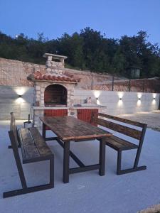 a picnic table and benches in front of a brick oven at Village House DIMS in Kotor