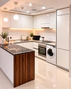 a kitchen with white cabinets and a washer and dryer at شقة برج رافال Rafal Tower in Riyadh