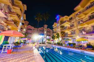 a swimming pool in front of buildings at night at Joystays Renton Manor in Arpora