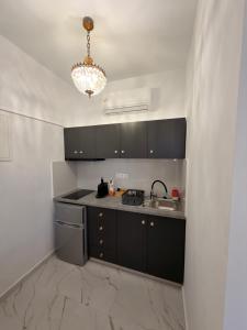 a kitchen with black cabinets and a sink and a chandelier at Mykonos Secret Spot in Mikonos