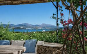 a view of the water from a garden with a bench at Amazing Two-Bedroom House with Sea View in Cala di Volpe in Porto Cervo