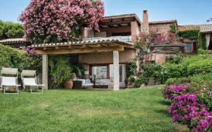 a house with two chairs and flowers in the yard at Amazing Two-Bedroom House with Sea View in Cala di Volpe in Porto Cervo +10 photos