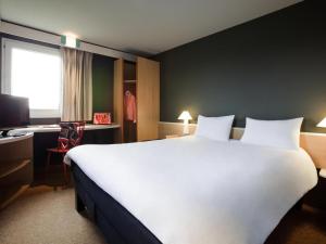 a hotel room with a large white bed and a desk at Ibis Provins in Provins +24 photos