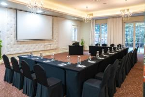 a conference room with a long table and chairs and a screen at Korona Hotel in Ostrołęka