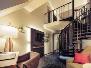 a living room with a staircase and a couch at Mercure München City Center in Munich