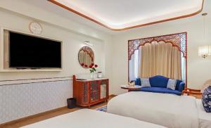 a hotel room with a bed and a flat screen tv at Bhagirathi By Atishay in Haridwār