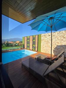 a patio with a pool and a blue umbrella at Blue Sky Private Pool Villa in Chiang Mai