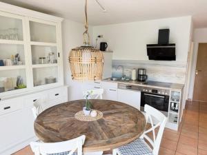 a kitchen with a wooden table and white chairs at Haus Katharina, Balkon mit Meerblick in Lauterbach +8 photos
