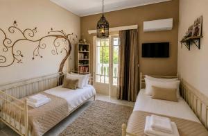 a bedroom with two beds and a tv on the wall at Allegoria House in Nafplio