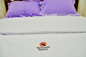 a bed with purple pillows on top of it at Townside Suites in Kyebando