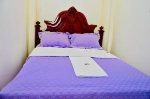 a purple bed with a wooden headboard and purple pillows at Townside Suites in Kyebando