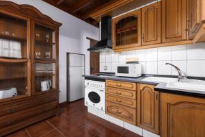 a kitchen with wooden cabinets and a white stove top oven at Home2Book La Molina A, Cozy Terrace Retreat in Triquivijate
