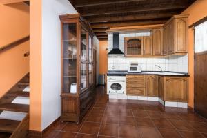 a kitchen with wooden cabinets and a stove top oven at Home2Book La Molina A, Cozy Terrace Retreat in Triquivijate