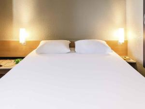 a large bed in a hotel room with two pillows at ibis Thonon Centre in Thonon-les-Bains +47 photos