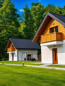 a house with a wooden roof and a lawn at Domek z balią Pod Dębem in Zabrzeź