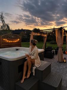 a woman sitting in front of a hot tub at Domek z balią Pod Dębem in Zabrzeź +1 photo