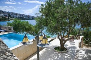 two lights next to a tree next to a swimming pool at LUXURY VILLA CIOVO Sleeps 17, Infinity Pool, Seafront in Trogir