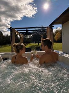 a man and woman sitting in a hot tub with wine glasses at Domek z balią Pod Dębem in Zabrzeź
