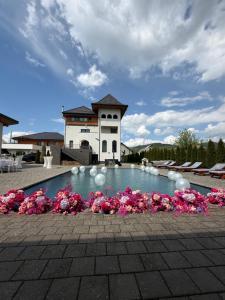 a swimming pool with pink flowers in front of a building at Pensiunea Maramures Guesthouse in Vişeu de Jos