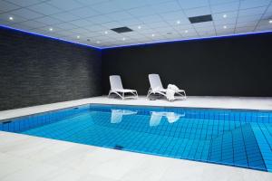a swimming pool with two white chairs next to it at Scandic Hvidovre in Hvidovre
