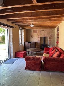 a living room with two red couches and a table at les hébergements de la ferme des buttons in Rosnay