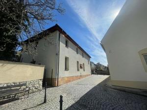 a white building with a brick sidewalk next to it at Hotel u Freuda Příbor in Nový Jičín