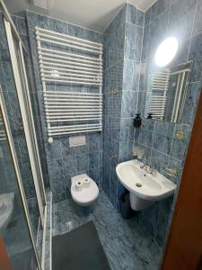 a blue tiled bathroom with a sink and a toilet at Hotel u Freuda Příbor in Nový Jičín
