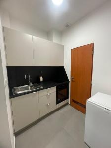 a kitchen with white cabinets and a sink and a door at Hotel u Freuda Příbor in Nový Jičín