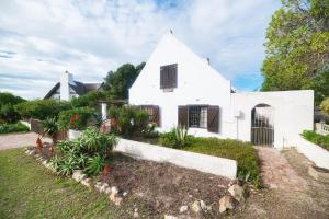 a white house with a garden in front of it at The Barn Main House in Arniston