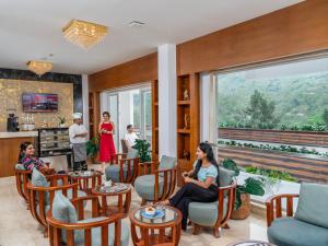 a group of people sitting in a room with a large window at The Grand Cliff Munnar Five Star Classified Resort in Munnar, Kerala in Viripara