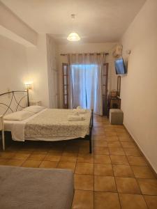 a bedroom with two beds and a window with a television at Arianna Studio Ground Floor 2 in Paleokastritsa