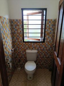 a bathroom with a toilet and a window at Peaceful Diani apartment in Diani Beach +9 photos