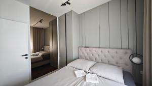 a bedroom with a bed with a headboard and a mirror at ModernApartmentsBL in Banja Luka